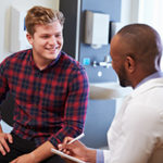 Male Patient And Doctor Have Consultation In Hospital Room