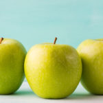 Three Green apples on turquoise background